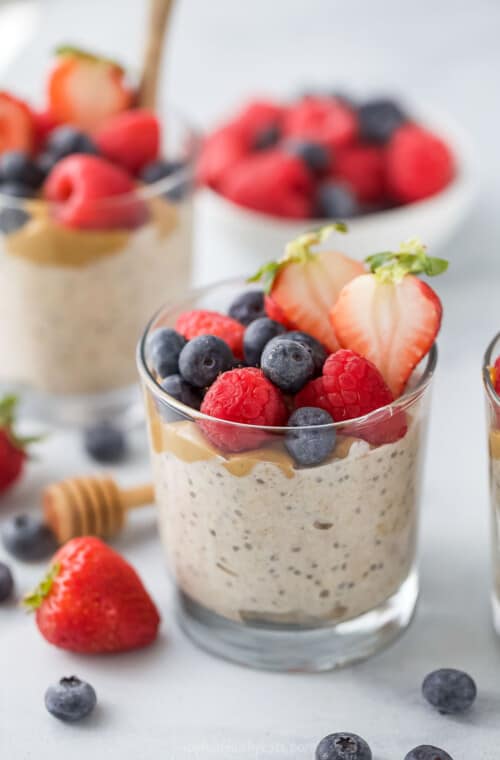 Overnight oats with yogurt in a glass with fresh berries on top.