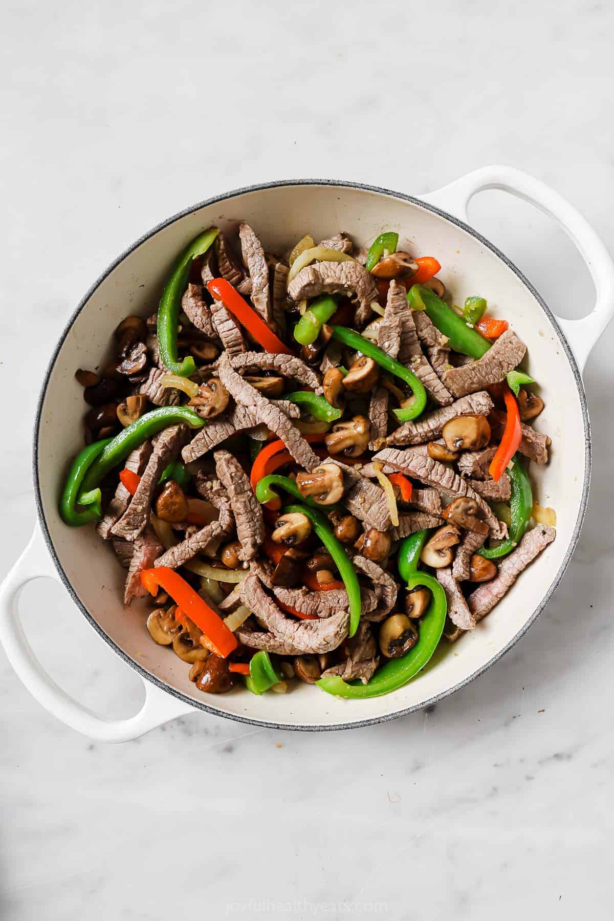 Combining the peppers with the steak and mushrooms. 