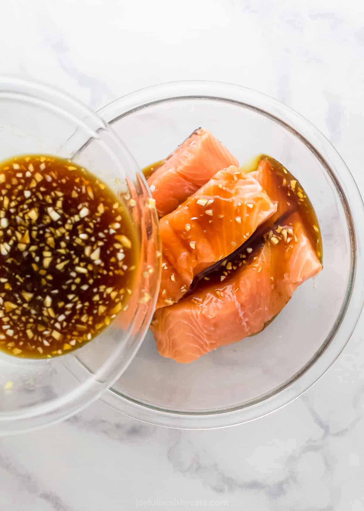 Pouring the marinade over the fresh salmon in a bowl. 