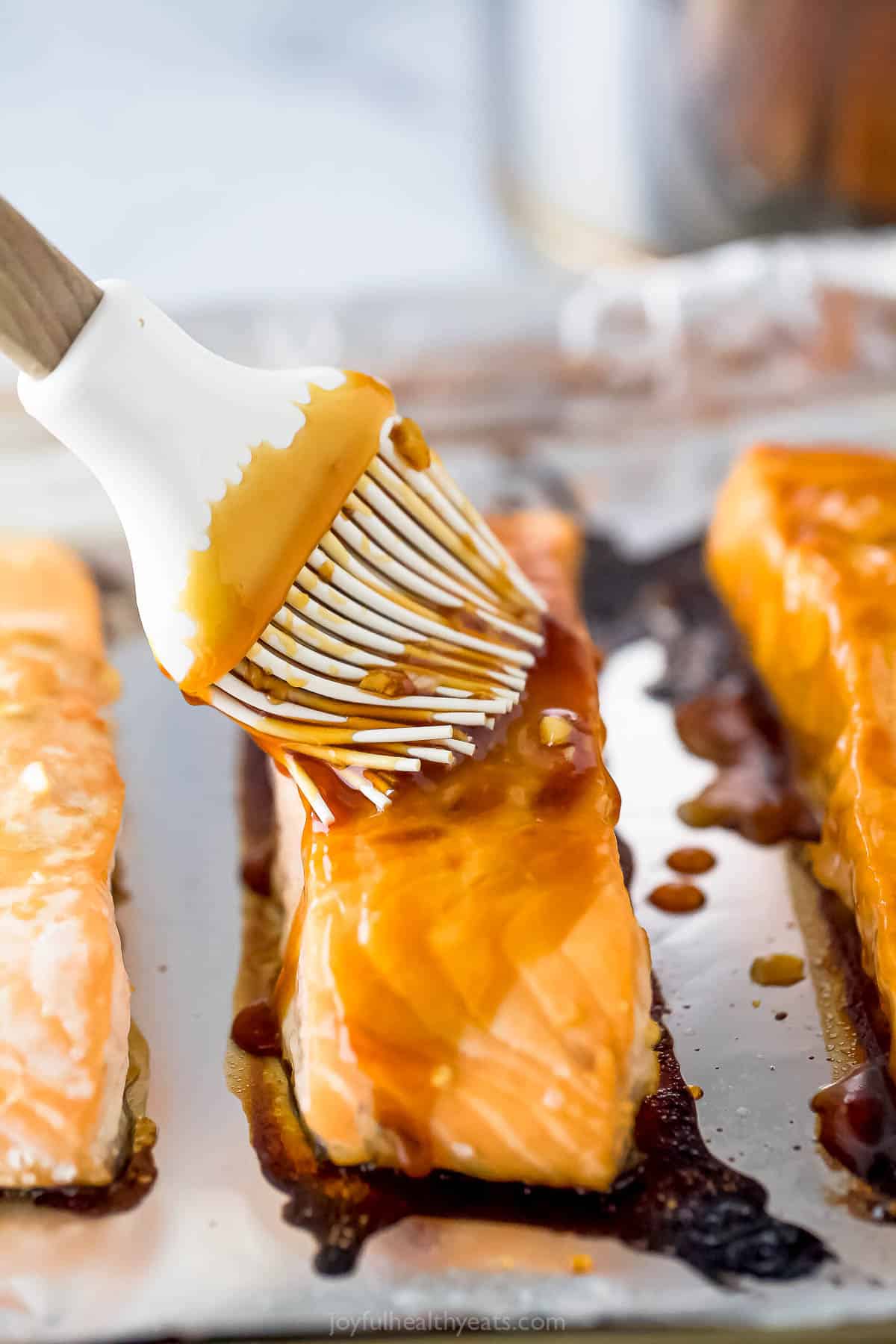 Brushing the teriyaki sauce over the cooked salmon. 