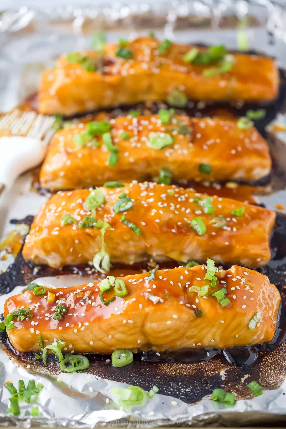 Close-up of salmon recipe with green onions and sesame seeds as garnishes. 