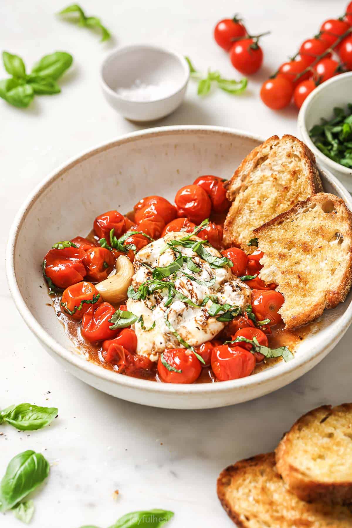 This 30-minute burrata caprese recipe with garlic, basil, and balsamic reduction is an easy, Italian-inspired appetizer. Bowl of burrata caprese with toasted sourdough and balsamic reduction.