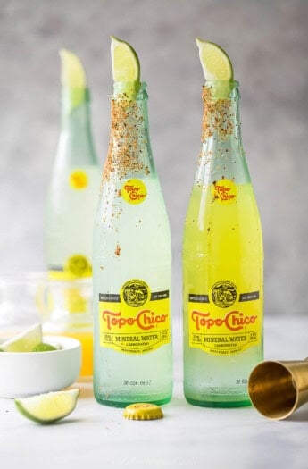Three bottles of ranch water recipe with lime wedges and a chili powder rim.
