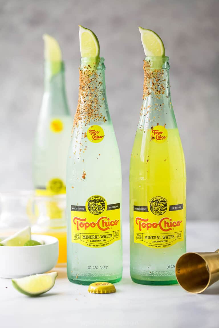 Three bottles of ranch water recipe with lime wedges and a chili powder rim.