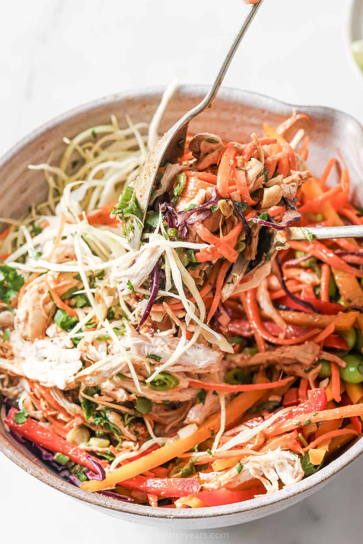 Stirring chopped Thai chicken salad in large bowl