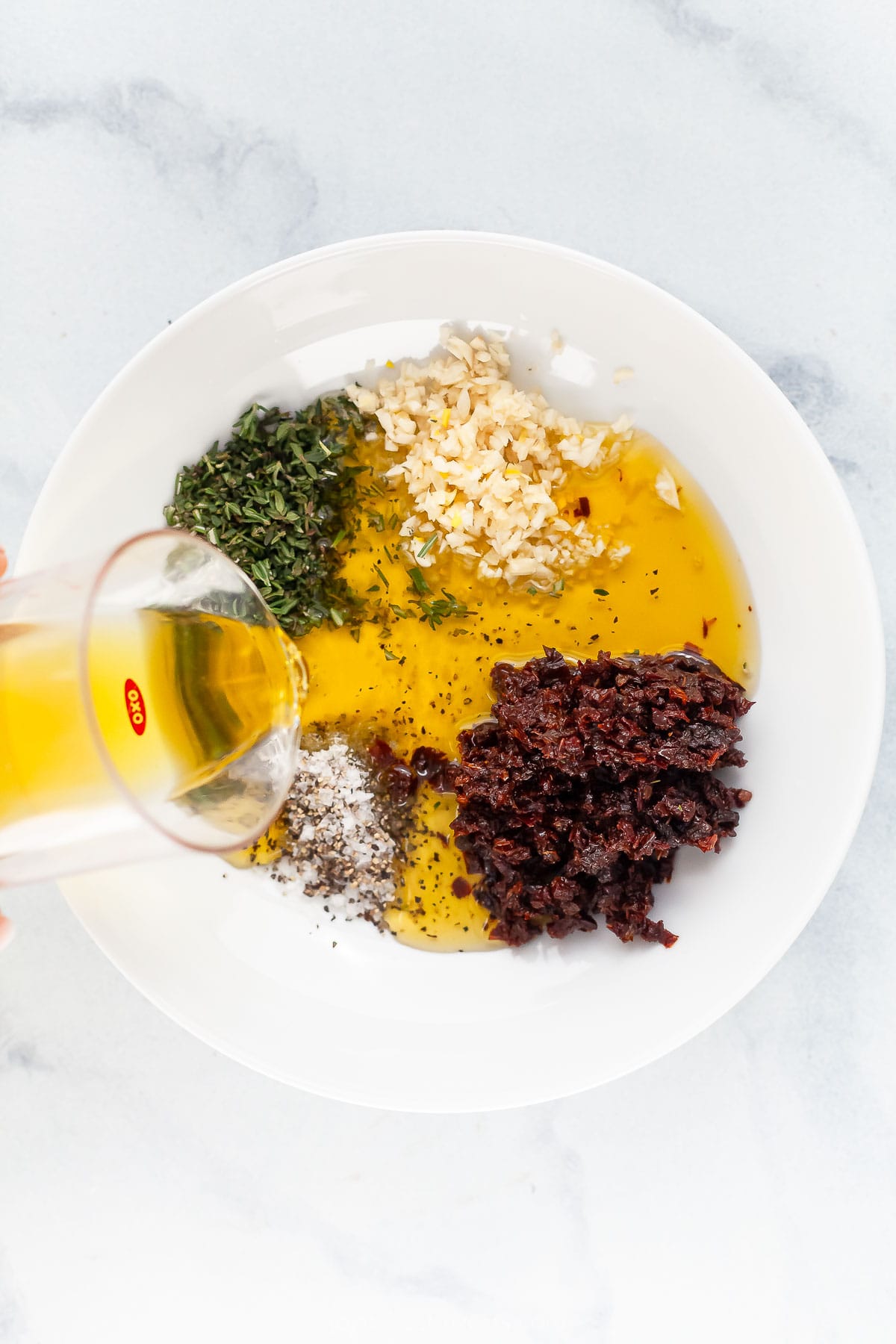 Pouring oil into bowl with ingredients for dipping oil