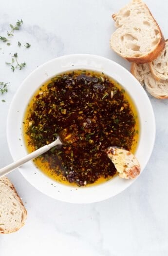 Overhead view of bread dipping oil in bowl with spoon