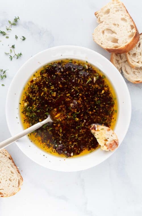 Overhead view of bread dipping oil in bowl with spoon