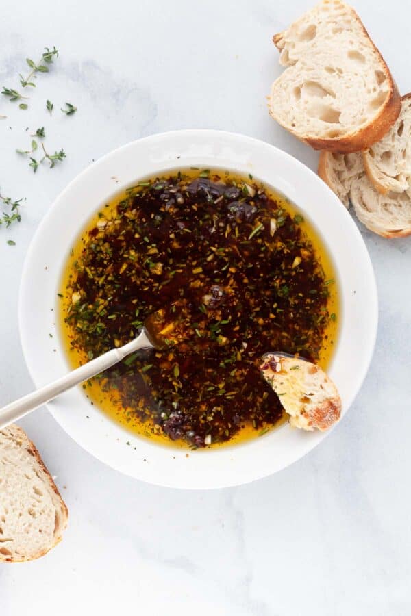 Overhead view of bread dipping oil in bowl with spoon