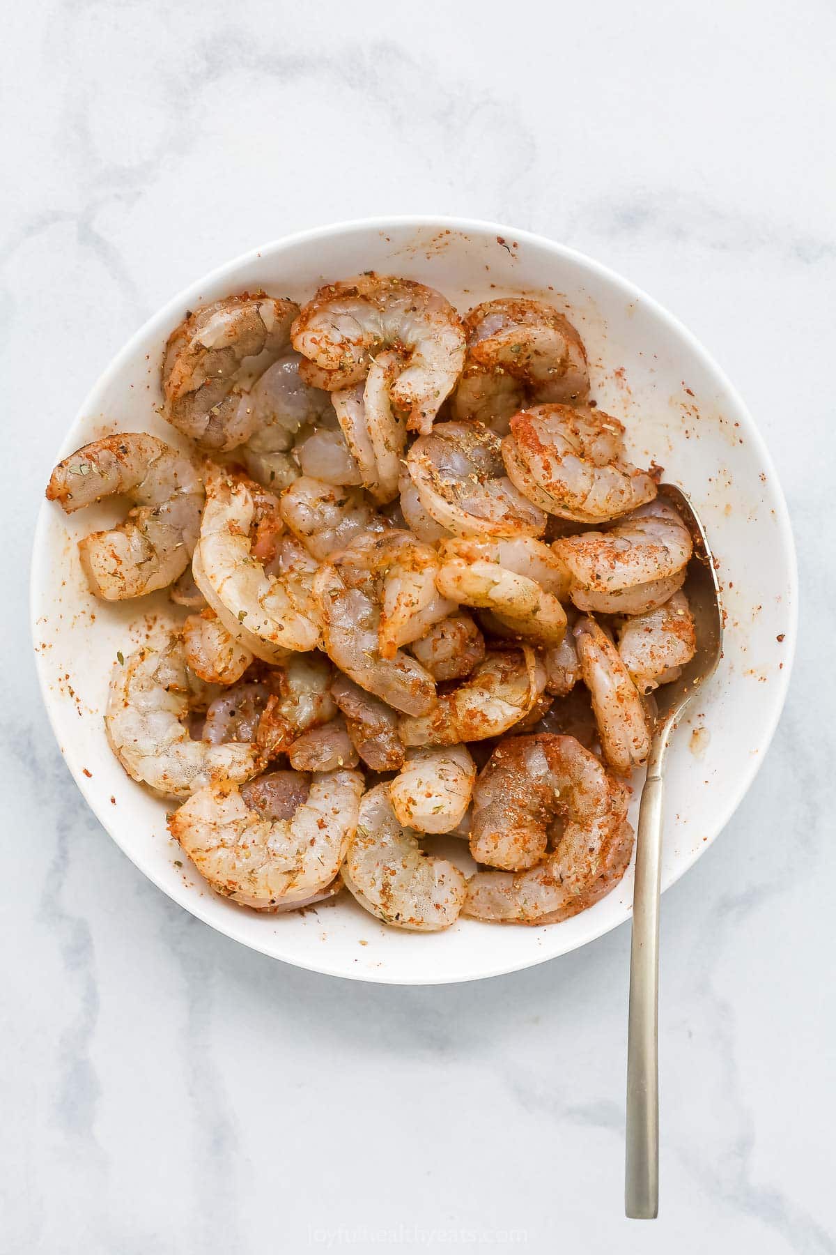 Overhead view of shrimp being tossed in seasonings