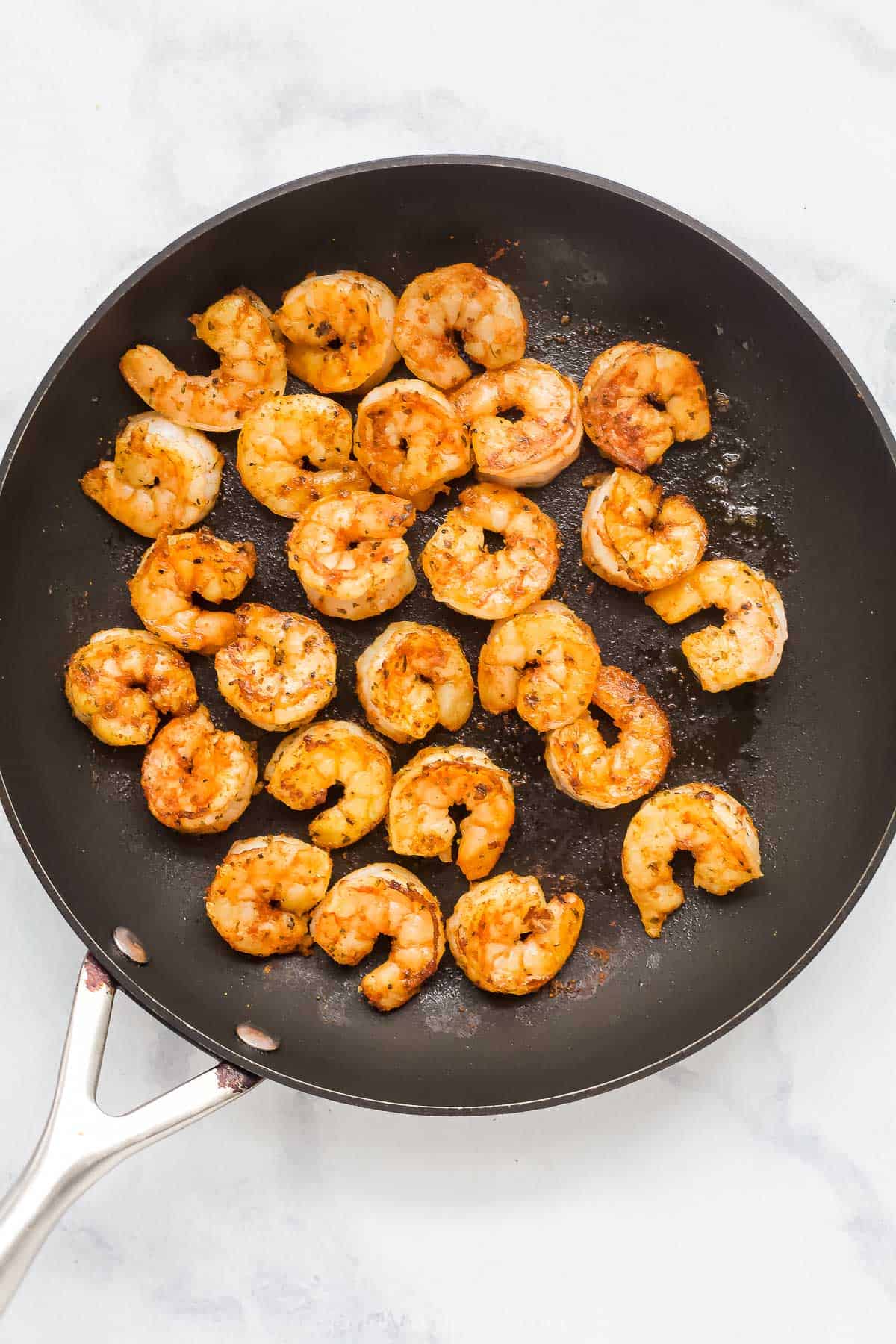 Overhead view of shrimp cooking in skillet