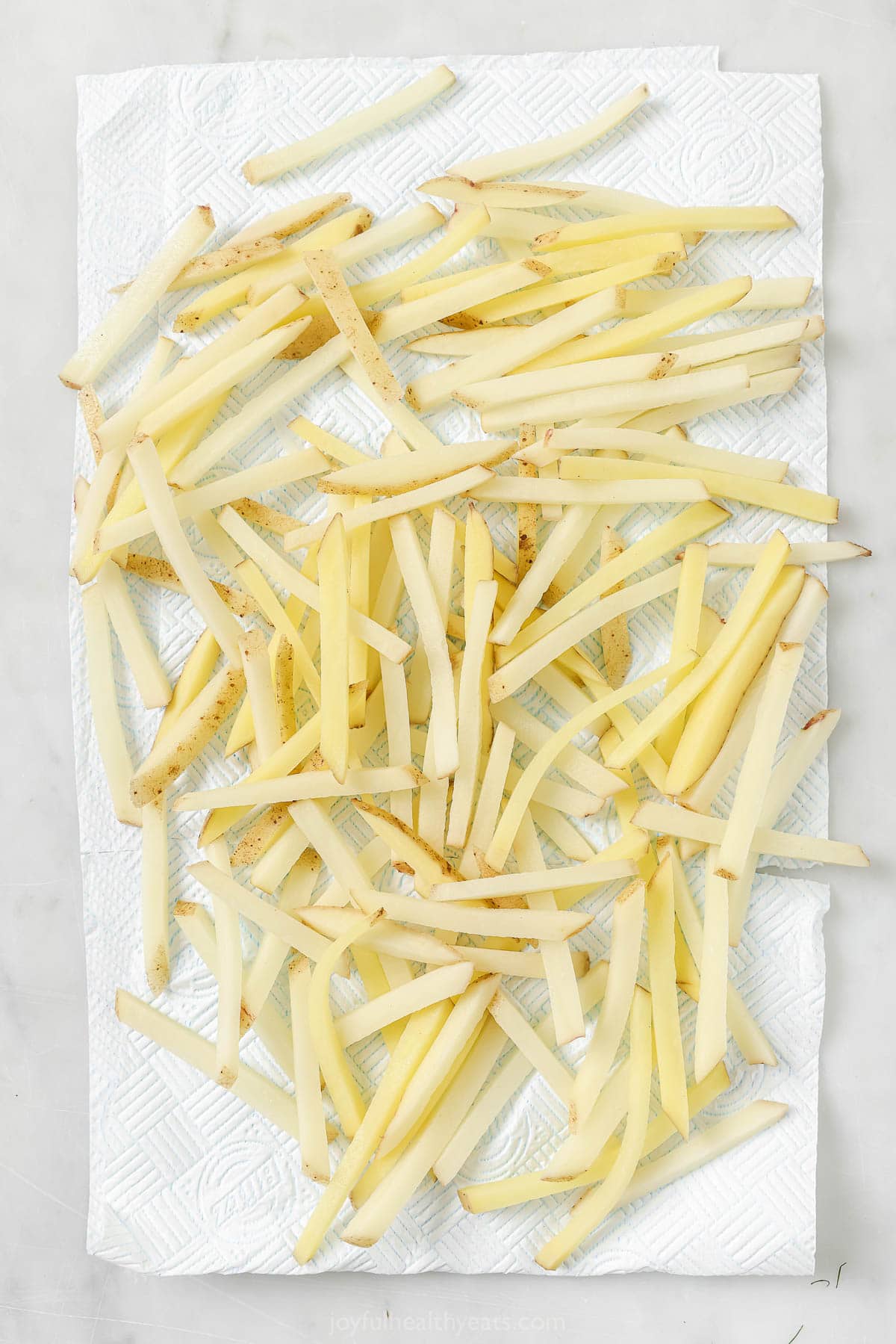 Cheesy Parmesan Truffle Fries are the perfect snack or party app when you’re feeling a little fancy. Baked in the oven and super crispy! Overhead view of cut fries draining on paper towels after soaking in water