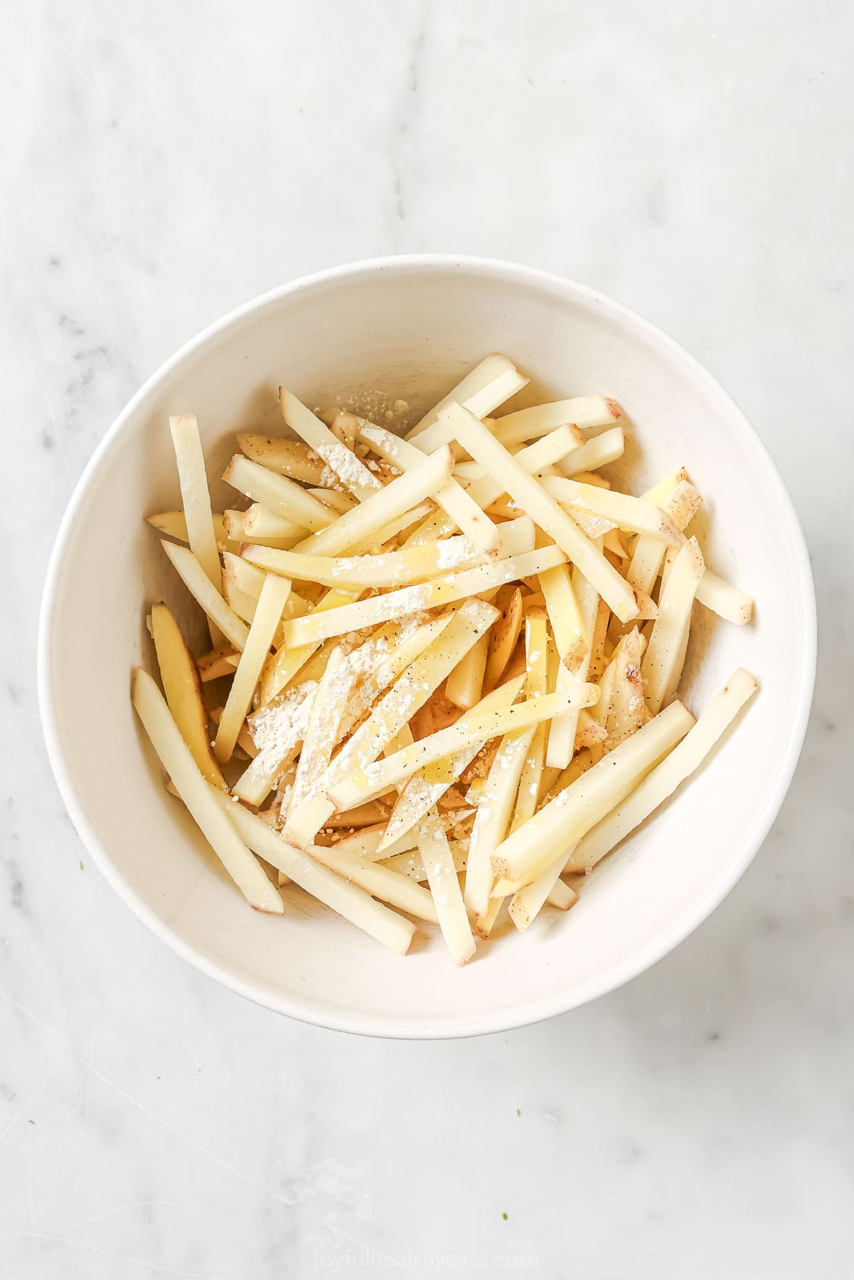 Cheesy Parmesan Truffle Fries are the perfect snack or party app when you’re feeling a little fancy. Baked in the oven and super crispy! Seasonings added to bowl of uncooked fries
