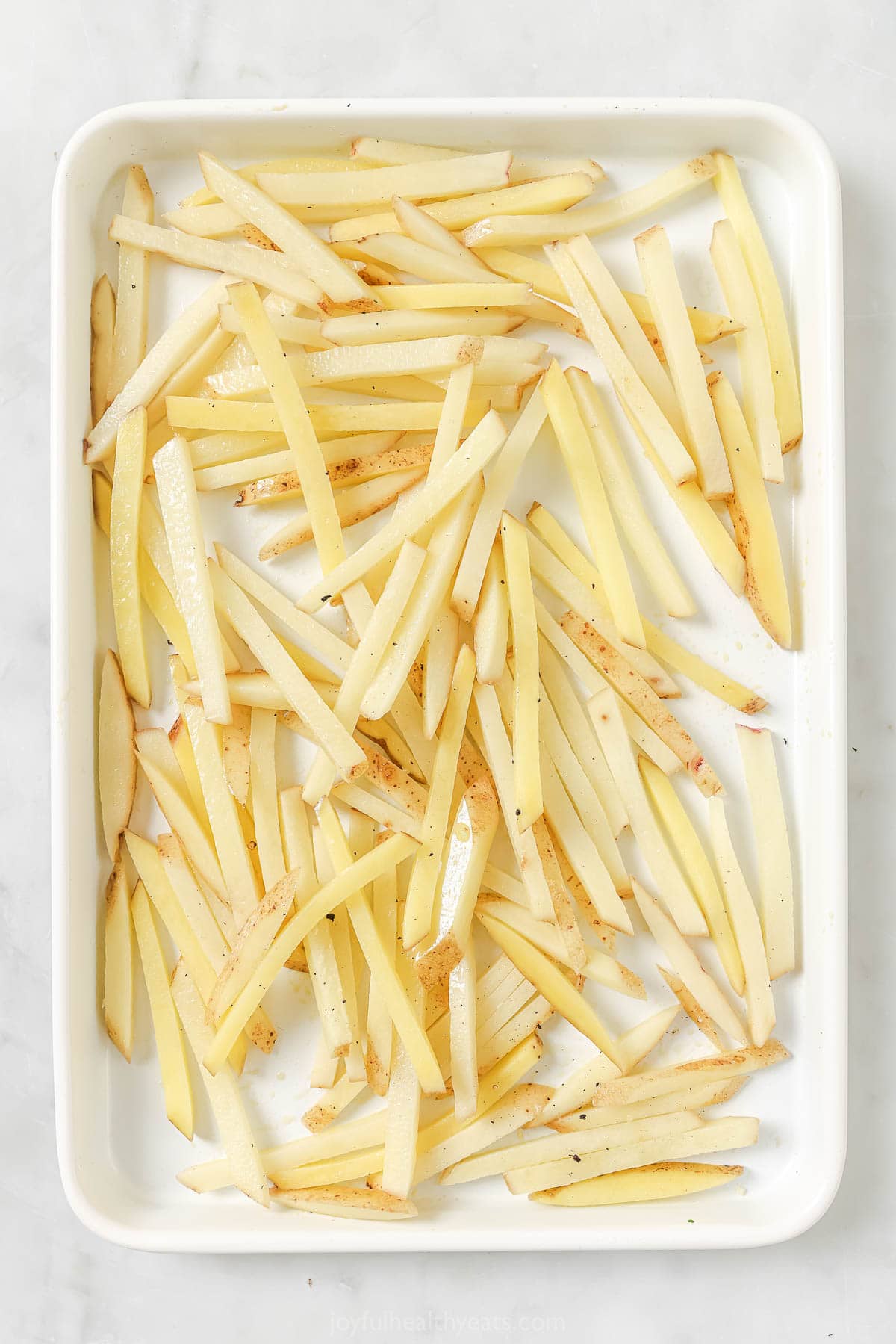 Cheesy Parmesan Truffle Fries are the perfect snack or party app when you’re feeling a little fancy. Baked in the oven and super crispy! Overhead view of unbaked fries on sheet pan