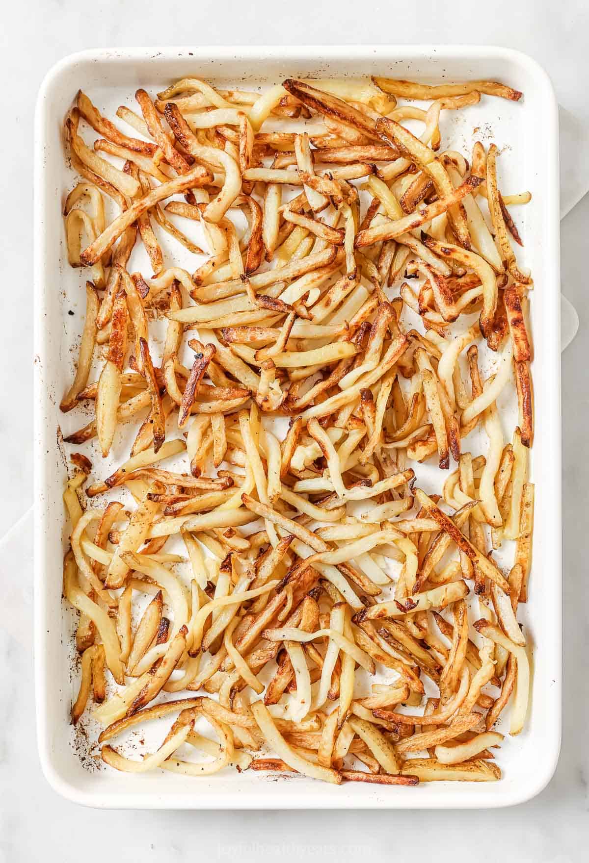 Cheesy Parmesan Truffle Fries are the perfect snack or party app when you’re feeling a little fancy. Baked in the oven and super crispy! Truffle fries on pan before garnishing