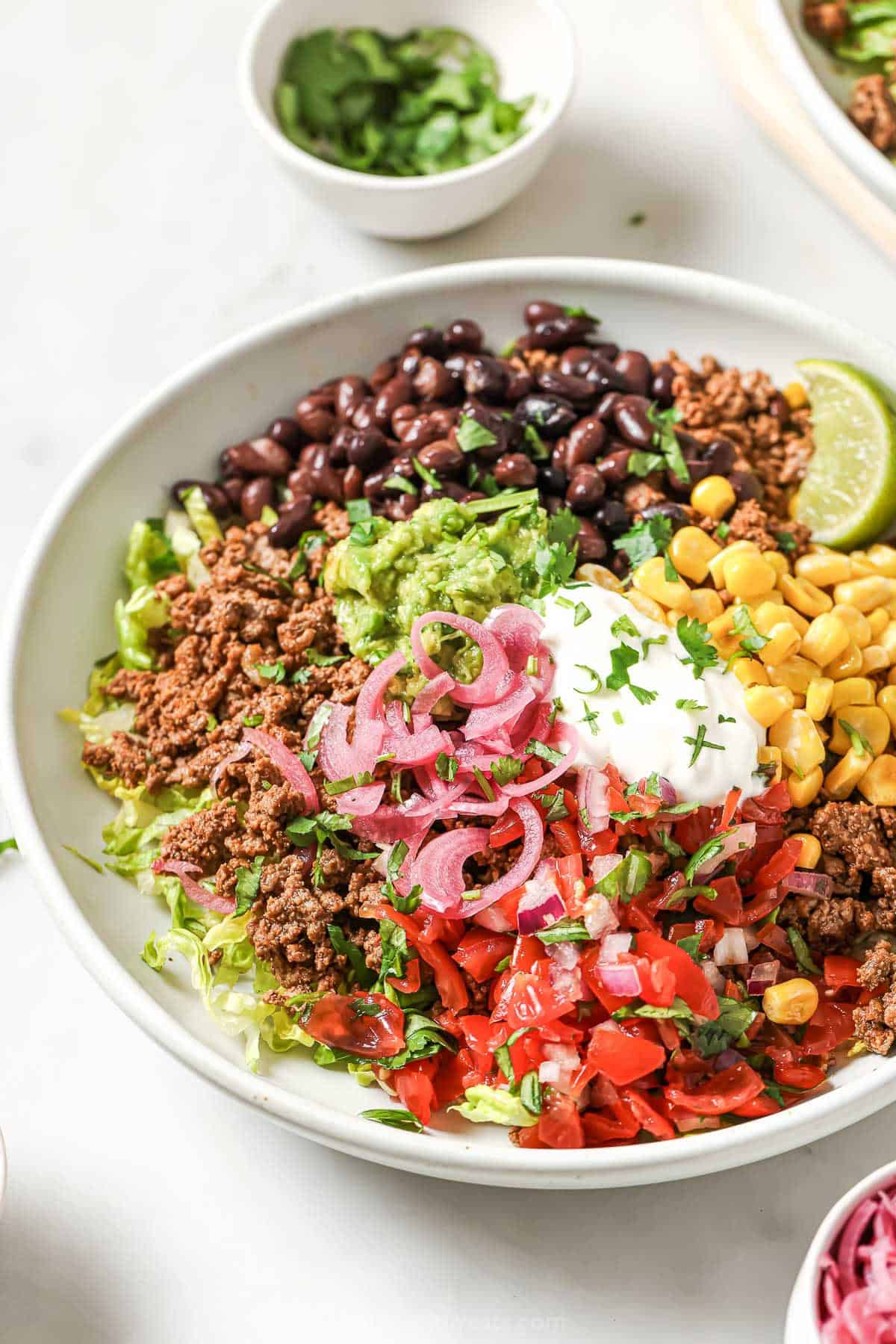 Taco salad bowl with sour cream, cilantro, and lime wedge for garnish