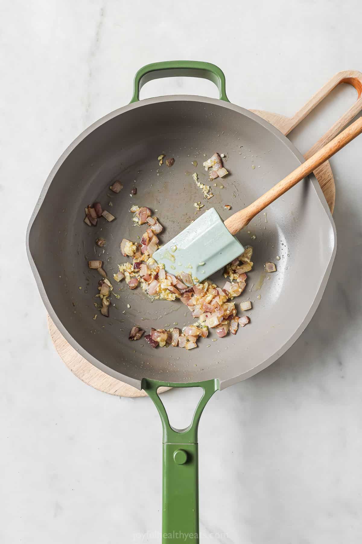 Overhead view of onion and garlic cooking in skillet