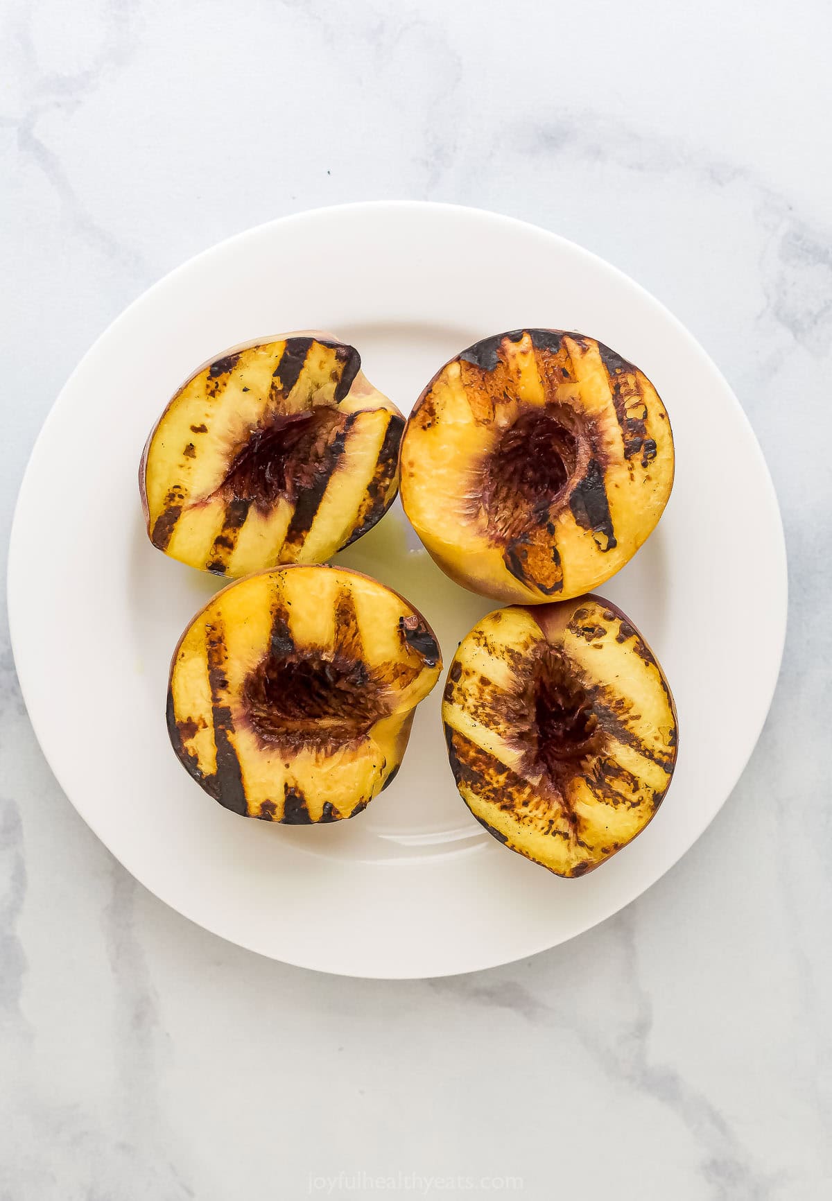 Overhead view of grilled peaches on plate