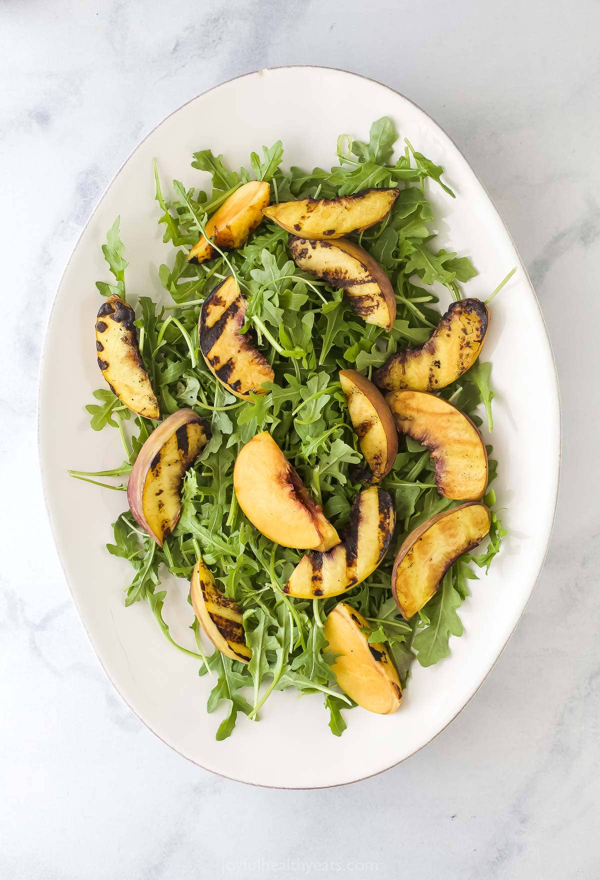 Overhead view of arugula and peaches on platter
