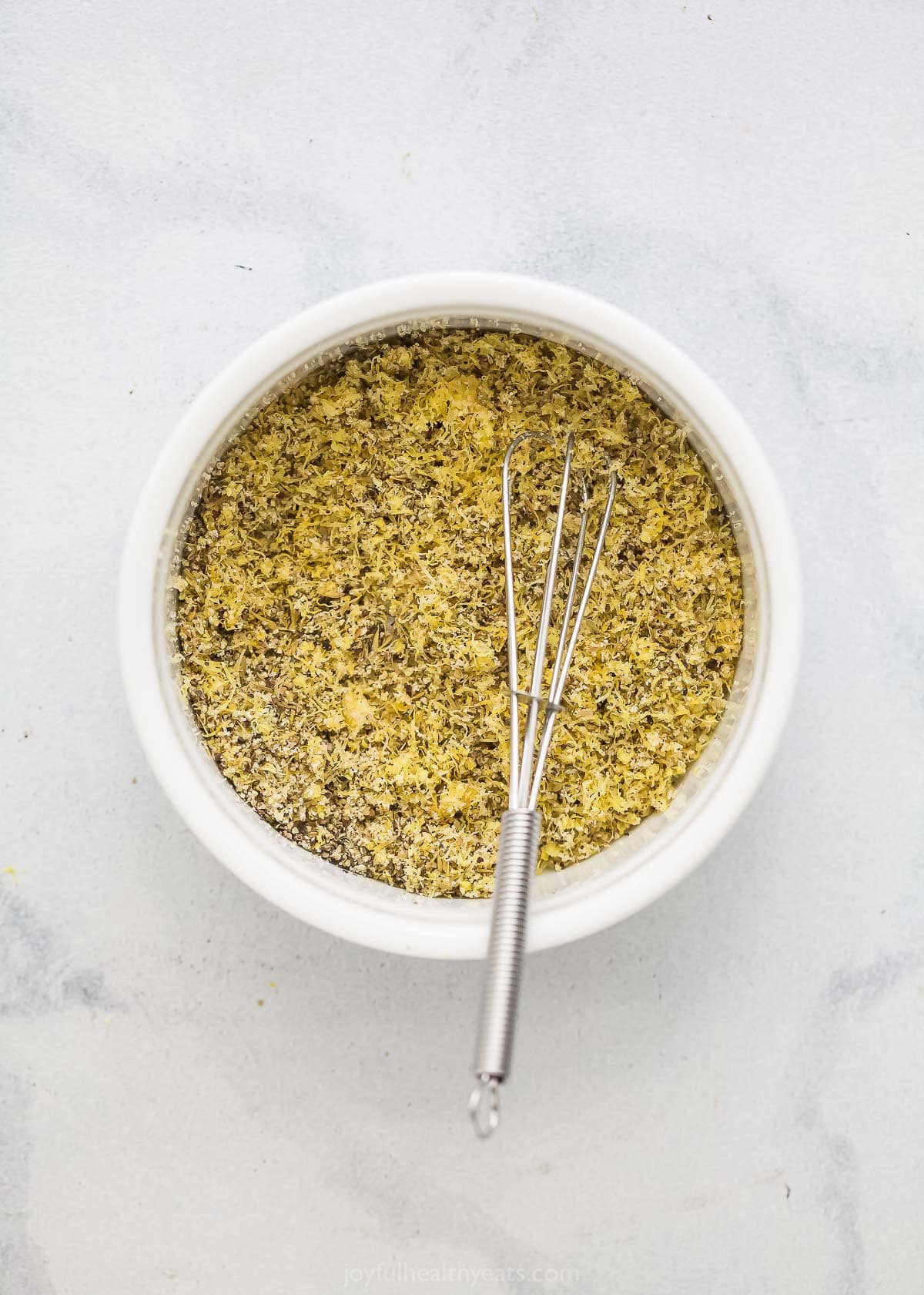 Add a pop of citrus to chicken, seafood, and more with this easy homemade Lemon Pepper Seasoning. It's so much tastier than store-bought! Overhead view of lemon pepper seasoning in bowl with whisk