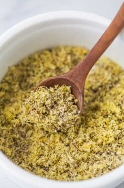 Wooden spoon scooping lemon pepper seasoning from bowl
