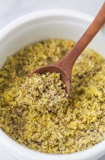 Wooden spoon scooping lemon pepper seasoning from bowl