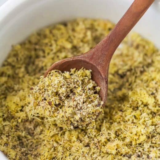 Wooden spoon scooping lemon pepper seasoning from bowl