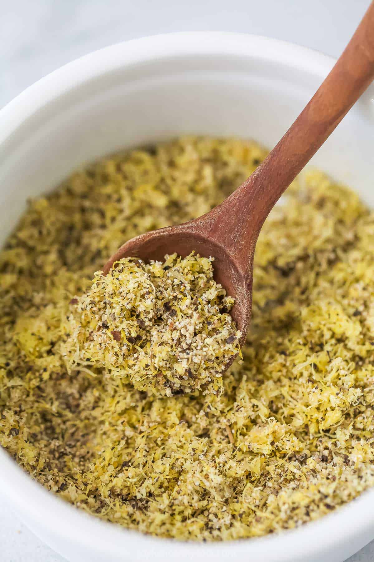 Add a pop of citrus to chicken, seafood, and more with this easy homemade Lemon Pepper Seasoning. It's so much tastier than store-bought! Wooden spoon scooping lemon pepper seasoning from bowl
