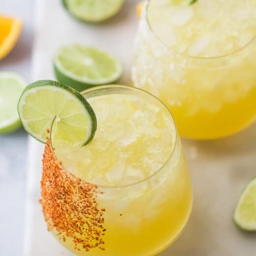 Two glasses of margarita mocktail with lime wheels and Tajin