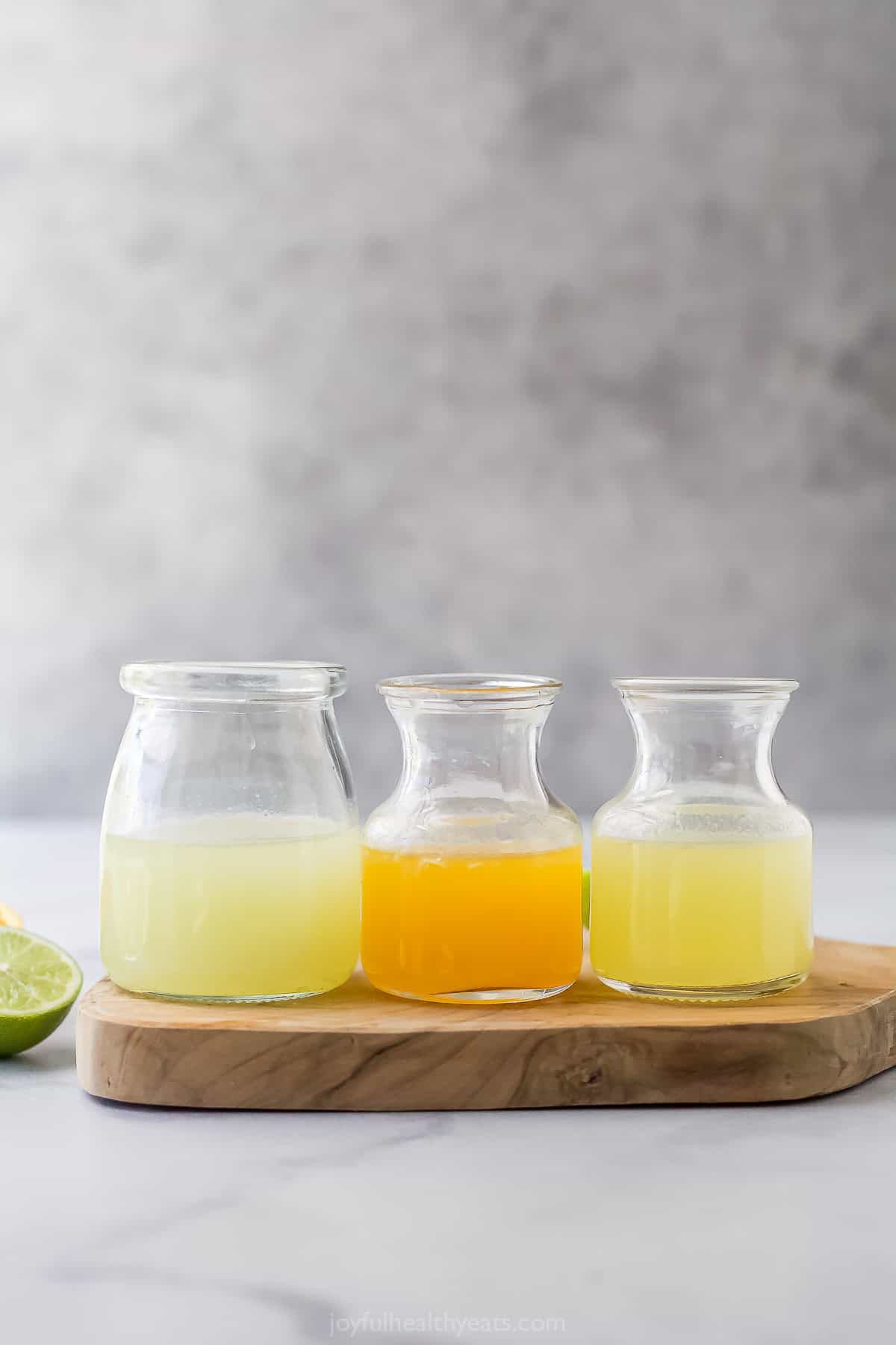 This Margarita Mocktail recipe is made without the alcohol but ALL the flavor, with a blend of fresh citrus juice, agave and sparkling water. Three glass bottles with lime, orange, and lemon juice