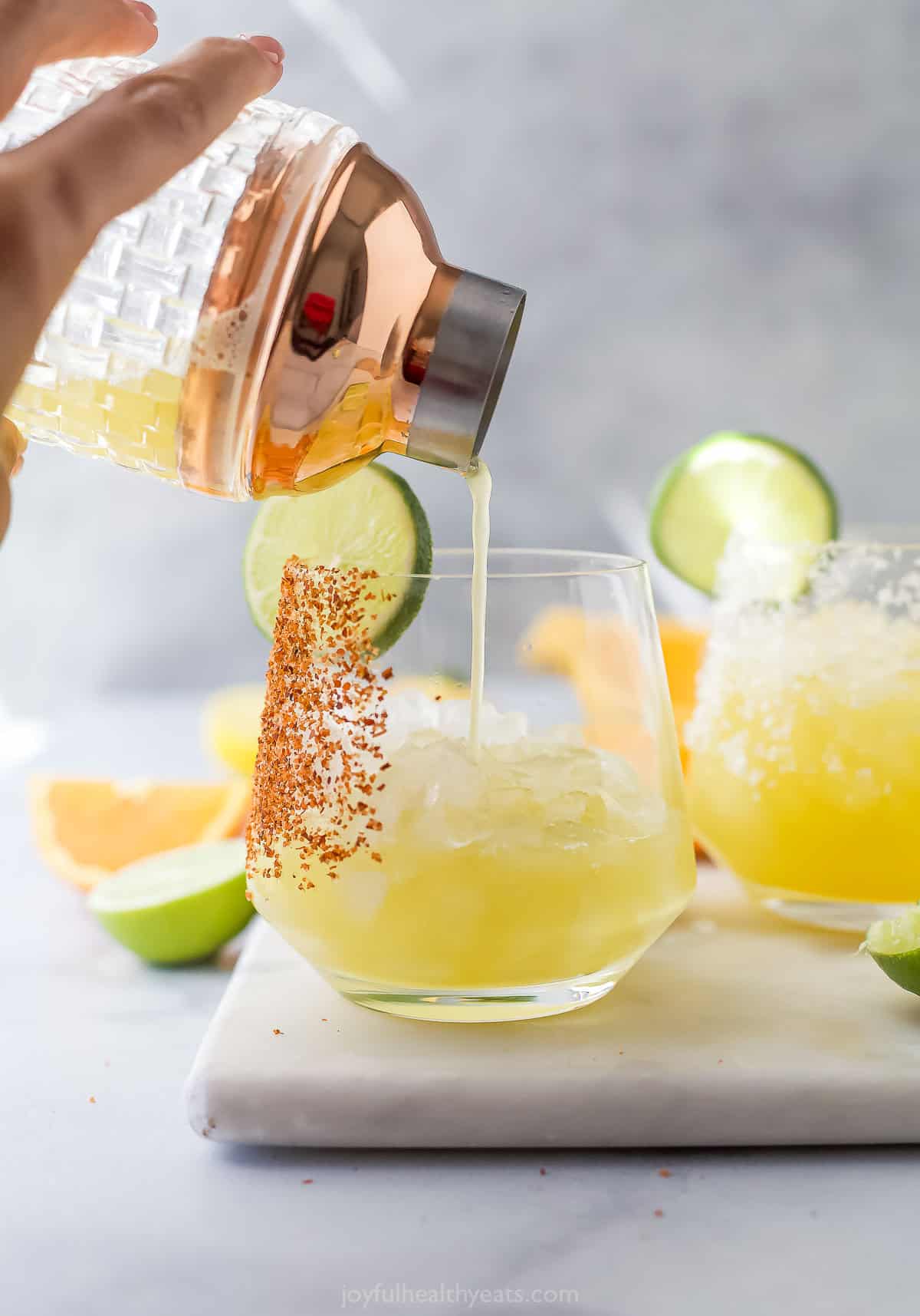This Margarita Mocktail recipe is made without the alcohol but ALL the flavor, with a blend of fresh citrus juice, agave and sparkling water. Pouring citrus juice mixture from cocktail shaker into glass with ice