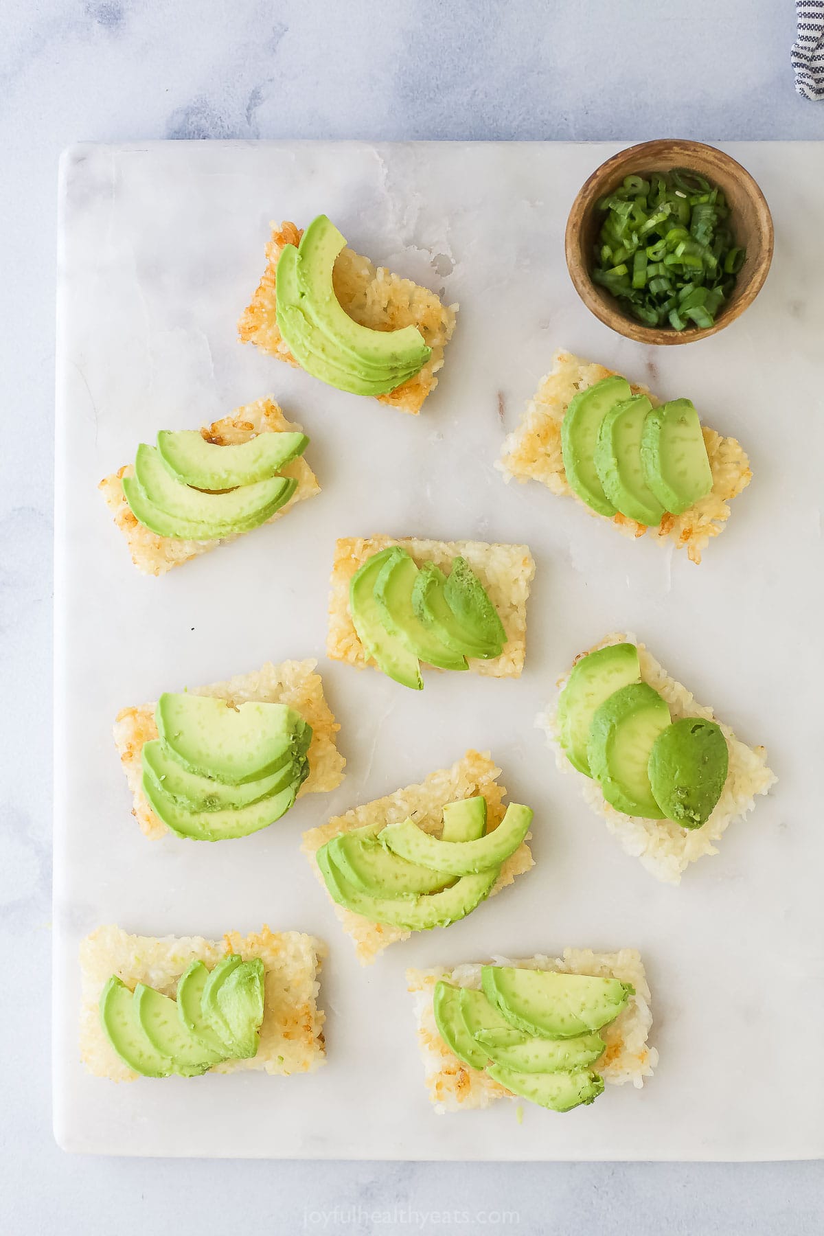 This Spicy Tuna Crispy Rice is a Nobu copycat that’s sure to impress! It’s easy to make, with ahi tuna topping crispy cubes of sushi rice. Overhead view of avocado added to crispy rice