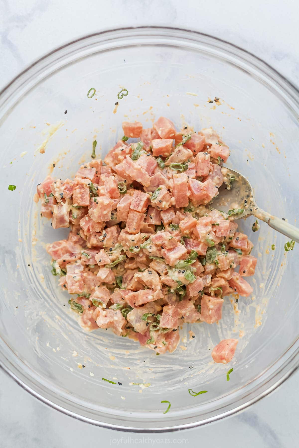 This Spicy Tuna Crispy Rice is a Nobu copycat that’s sure to impress! It’s easy to make, with ahi tuna topping crispy cubes of sushi rice. Overhead view of spicy tuna in glass bowl