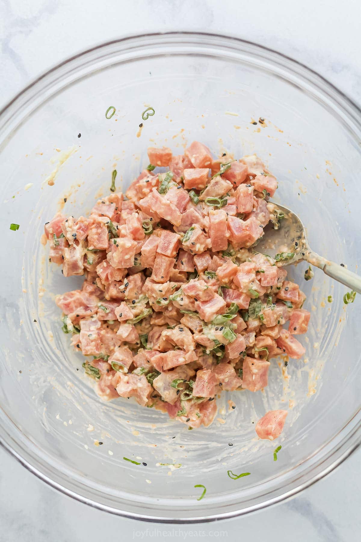 Stirring spicy tuna and sauce in glass bowl