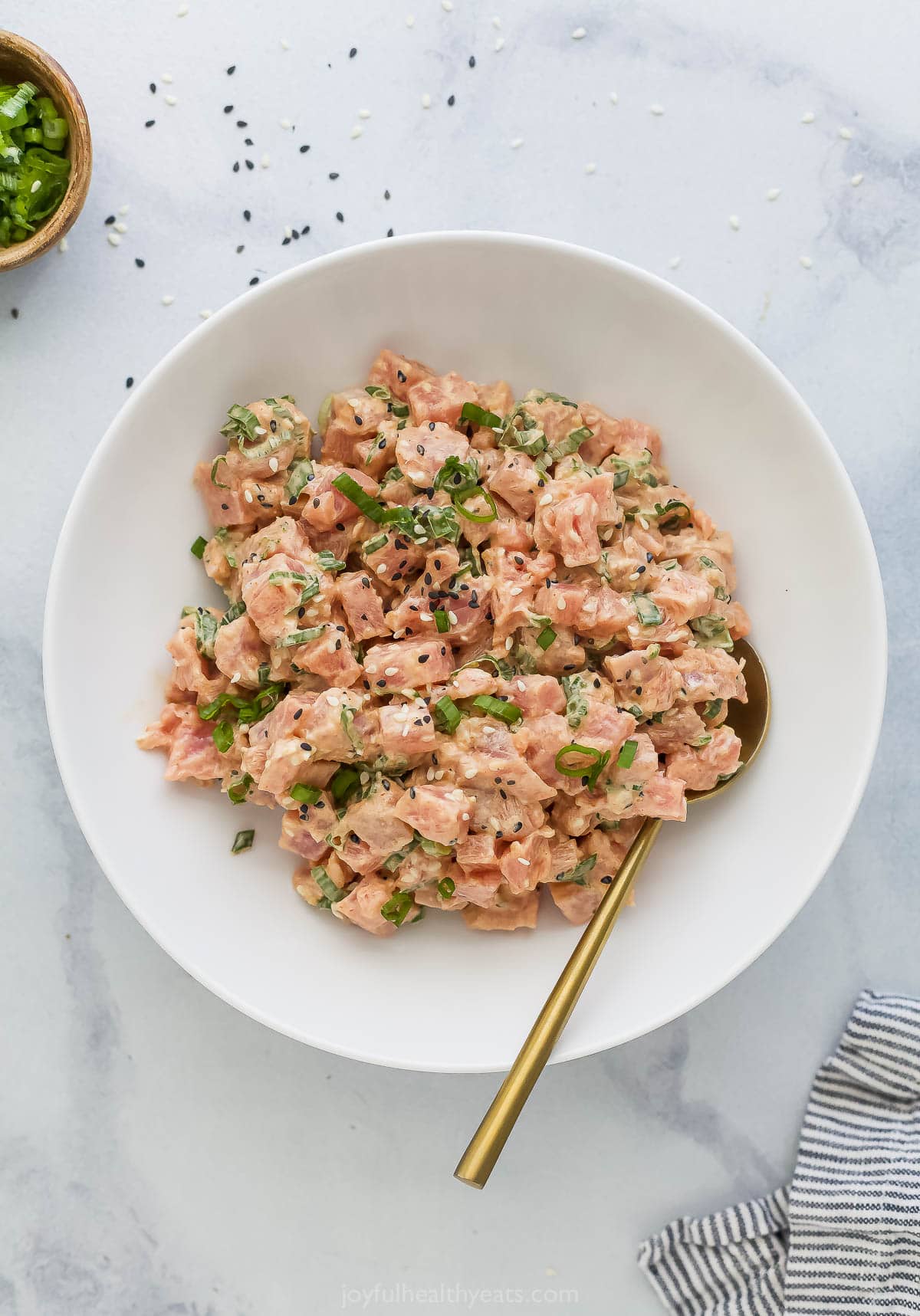 Spicy tuna is an easy Asian-style recipe that can be added to salad, meal bowls, sushi, and more. It's so simple, but SO delicious! Bowl of spicy tuna with gold spoon