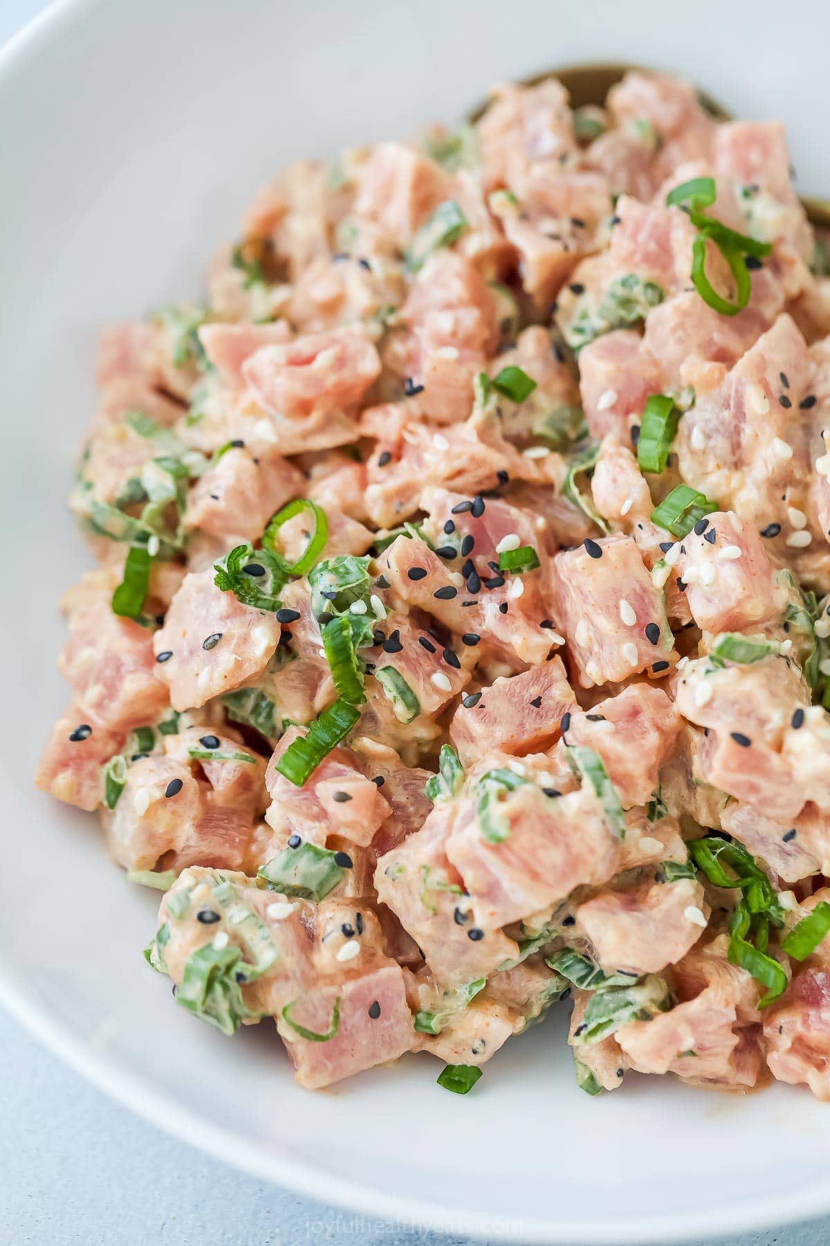 Spicy tuna is an easy Asian-style recipe that can be added to salad, meal bowls, sushi, and more. It's so simple, but SO delicious! Bowl of spicy tuna with sesame seeds
