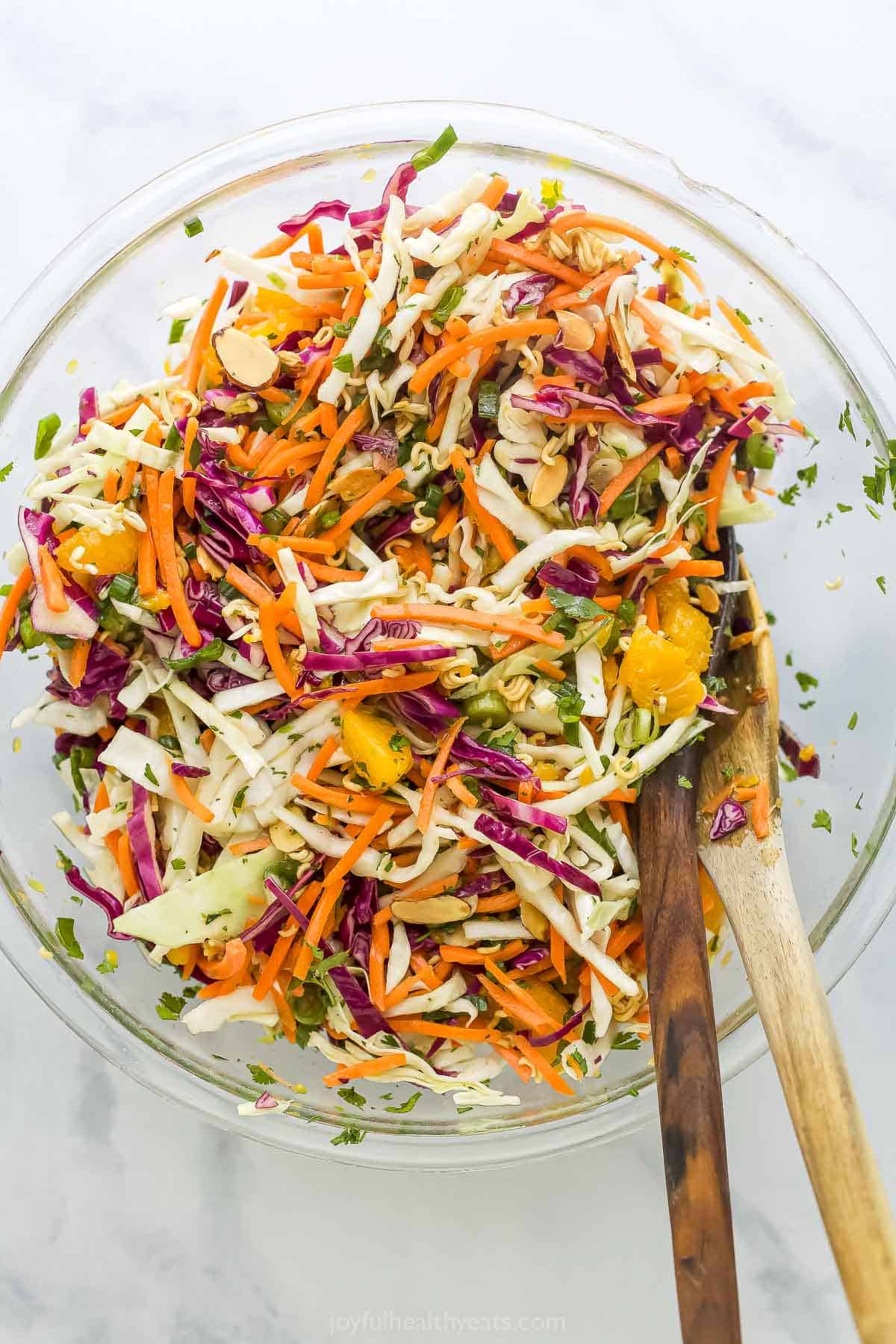 Crunchy, crisp, and sweet Ramen Noodle Salad is a classic! I’ve given it a more modern spin, but it still has that familiar flavor you love. Overhead view of ramen noodle salad in mixing bowl with wooden spoons