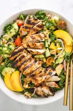 Overhead view of summer salad with grilled chicken in bowl with two forks