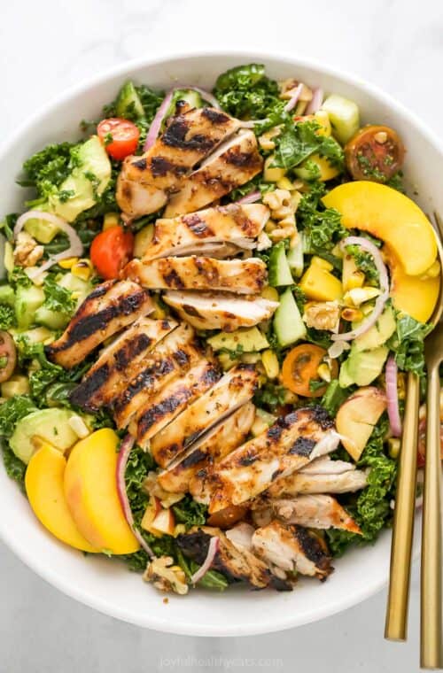 Overhead view of summer salad with grilled chicken in bowl with two forks