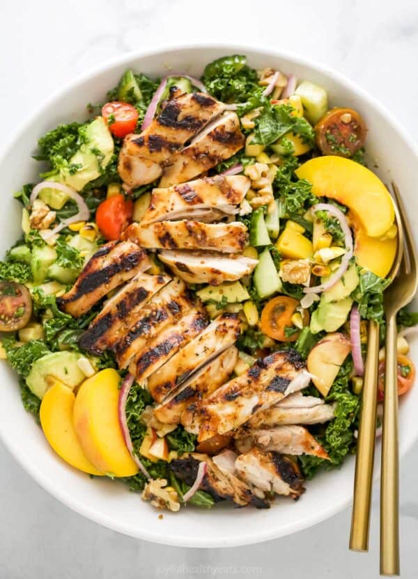 Overhead view of summer salad with grilled chicken in bowl with two forks