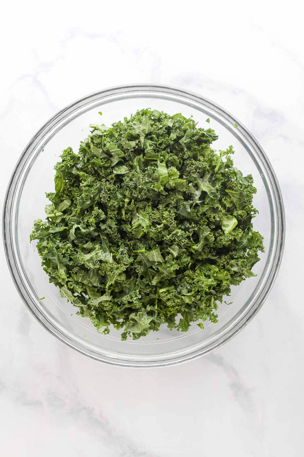 With sweet corn, peaches, tomatoes, grilled chicken and honey mustard dressing, this summer salad recipe is the perfect patio dinner! Overhead view of kale in glass bowl