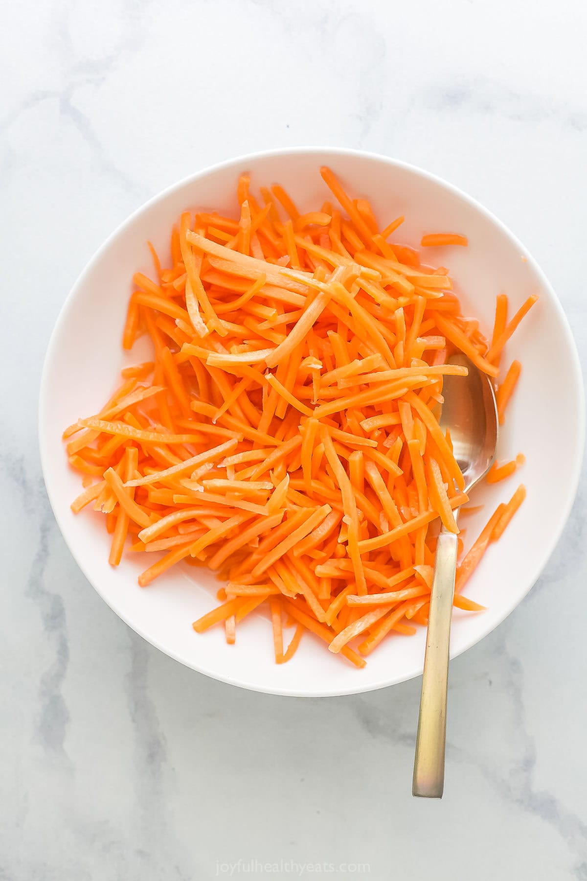 Overhead view of carrot pickles in bowl with spoon