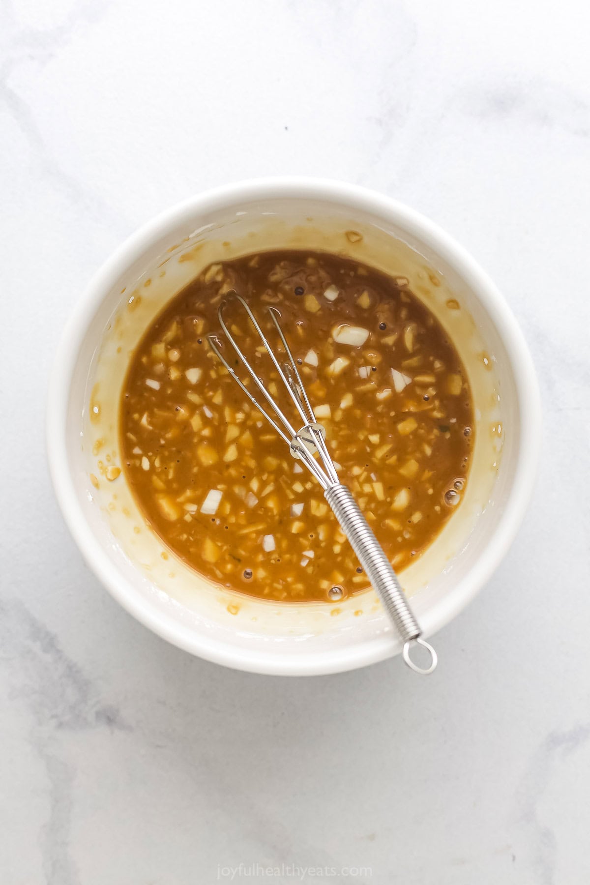Overhead view of sauce for ground turkey in bowl with whisk