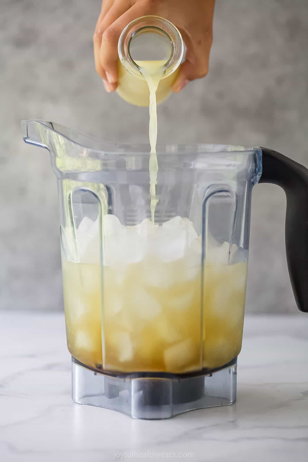 Pouring lime juice into blender full of ice