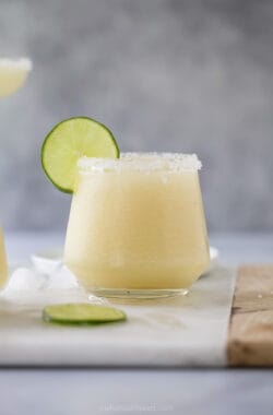 Frozen margarita in glass with salted rim and lime wheel