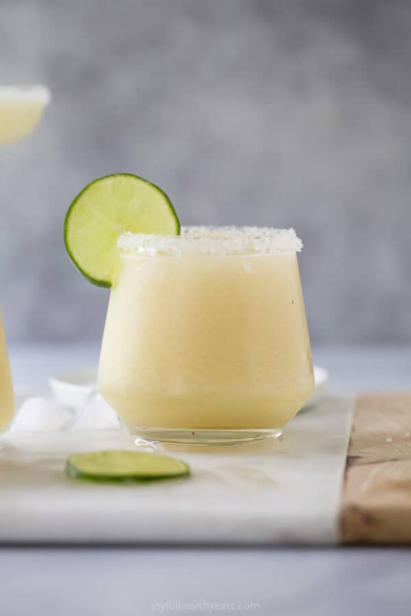 Frozen margarita in glass with salted rim and lime wheel