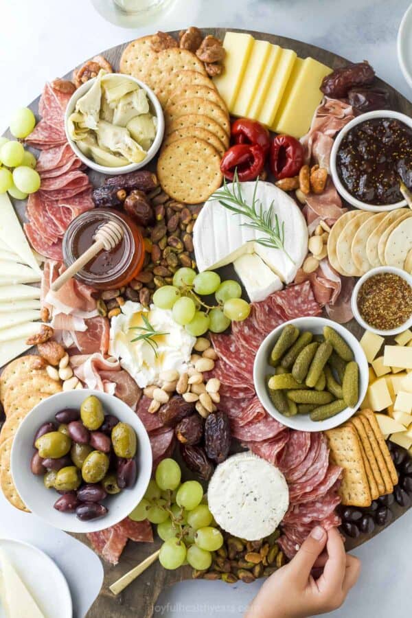Overhead view of hand pulling salami from charcuterie board