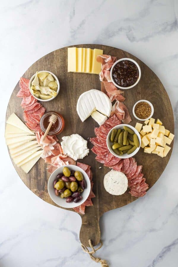 Overhead view of charcuterie board topped with meats, cheeses, and extras