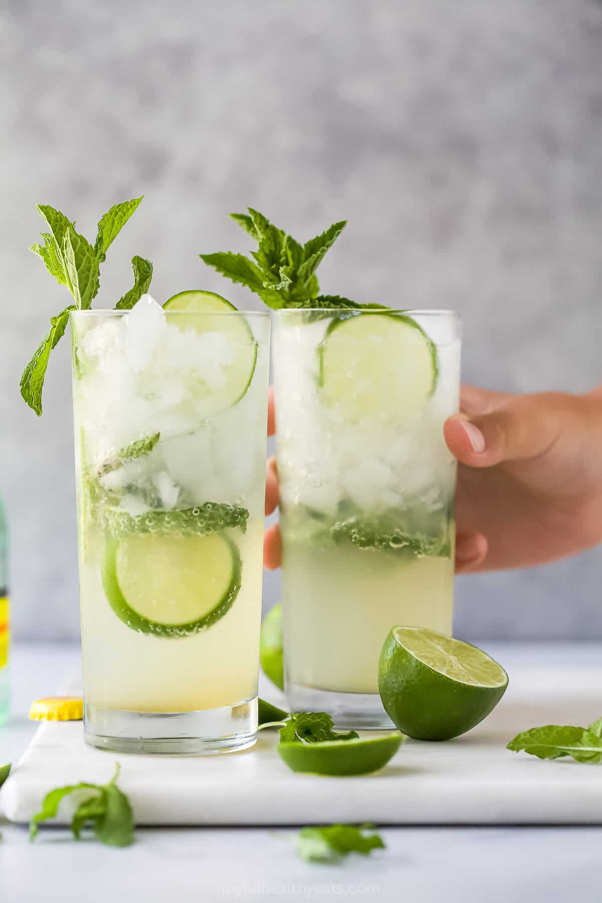 This Nojito recipe has everything you love about the original, minus the alcohol! Fresh mint, lime and sparkling water make it so refreshing. Hand grabbing nojito in glass