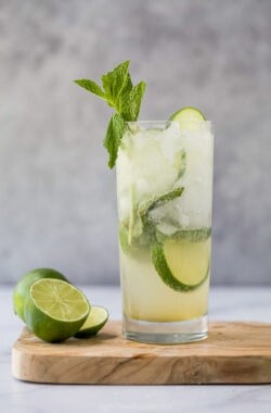 Nojito in glass on wooden cutting board with cut lime